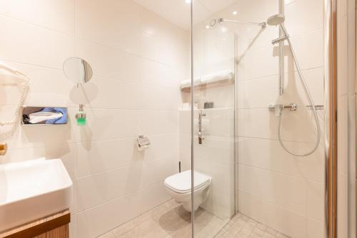 a bathroom with a toilet and a glass shower at Hotel Alphof Stubaital in Fulpmes