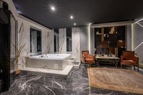 a bathroom with a tub and a table and a chair at Grand Hotel Sveti Vlas - Fitness & SPA Hotel in Sveti Vlas