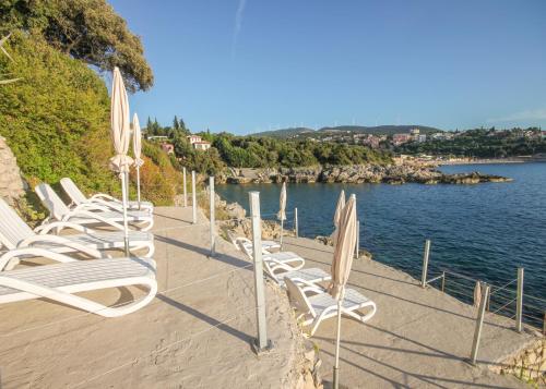 a row of chairs and umbrellas on a beach at Aleksandra Apartments Utjeha in Utjeha