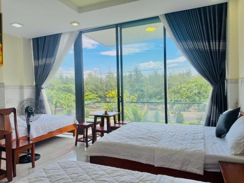 a bedroom with two beds and a large window at New Day Tuy Hòa in Liên Trì (4)