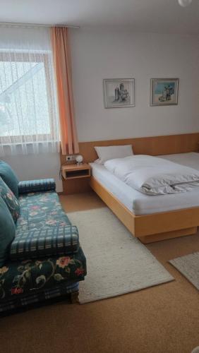 a bedroom with two beds and a couch and a window at PensionSchilling in Grasbrunn