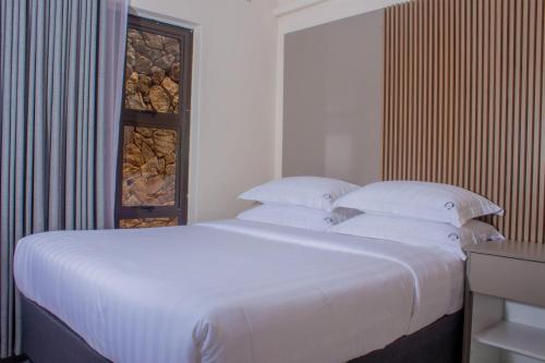 a large white bed with white pillows in a bedroom at Samanyanga Resort in Kariba