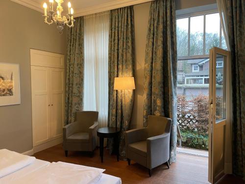 a hotel room with a bed and two chairs and a window at Villa Waldfrieden - Design trifft Budget in Annweiler am Trifels