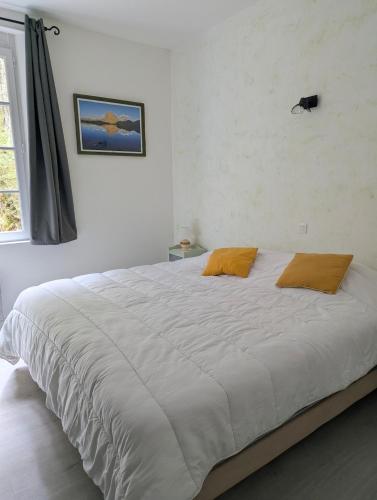 a bedroom with a large white bed with two orange pillows at Logement charmant à la montagne in Eaux-Bonnes