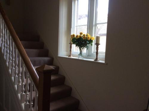 a staircase with a vase of yellow flowers in a window at Castle Farm House B&B in Corby
