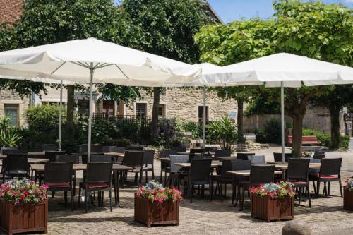 un patio con tavoli, sedie e ombrelloni di Relais de Bèze a Bèze