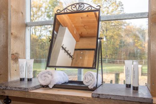 a mirror on a window sill with towels and candles at Schaapskooi in Maarsbergen