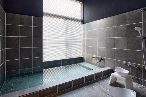 a bathroom with a tub with a toilet and a sink at 修善寺あざみ Luxury Japanese Villa with Mt Fuji Views and Onsen in Izu