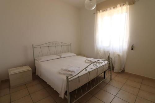 a bedroom with a bed with white sheets and a window at Casa Giselle in Otranto in Otranto