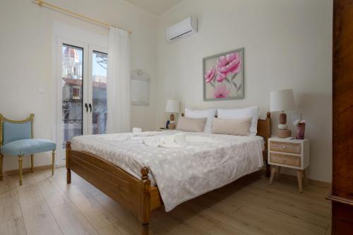 a white bedroom with a large bed and a window at Athenais Two Storey House in Zakynthos