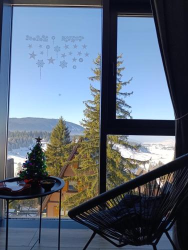 a room with a window with a chair and a christmas tree at Vlašić Grand View in Vlasic