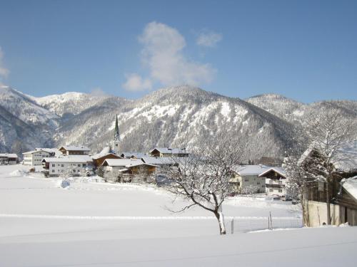 a village in the snow with mountains in the background at Hotel Neuwirt in Brandenberg