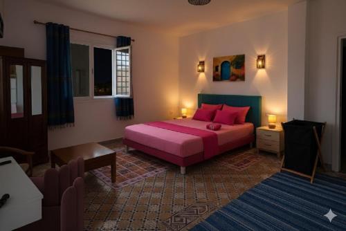 a bedroom with a bed with pink pillows at Villa Mabrouka in Raʼs al Jabal