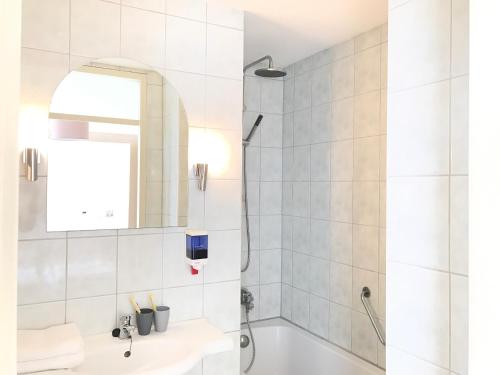 ein Badezimmer mit einer Badewanne, einem Waschbecken und einem Spiegel in der Unterkunft Hotel van Oppen in Zierikzee
