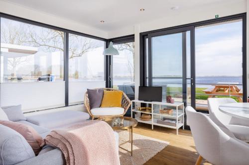 a living room with a couch and chairs and windows at Welcome in - Houseboat Agua Dolce met tuin, Paviljoenwei 4, Sneek - Offingawier in Offingawier