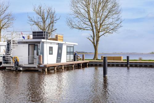 a small house on a dock on a body of water at Welcome in - Houseboat Agua Dolce met tuin, Paviljoenwei 4, Sneek - Offingawier in Offingawier
