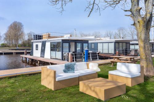 a house on the water with two chairs and a table at Welcome in - Houseboat Agua Dolce met tuin, Paviljoenwei 4, Sneek - Offingawier in Offingawier
