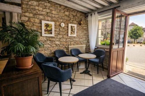 una stanza con tavoli e sedie e un muro di mattoni di Relais de Bèze a Bèze