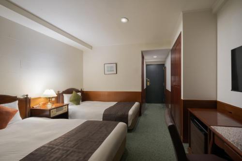 a hotel room with two beds and a flat screen tv at Premier Hotel -CABIN- Asahikawa in Asahikawa