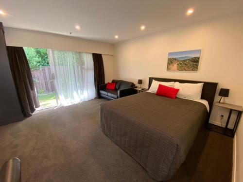 a bedroom with a bed and a chair and a window at Paraparaumu Motel in Paraparaumu