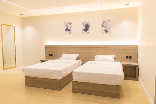 a bedroom with two beds and a mirror at وساد الشمال للشقق الفندقية in Hail