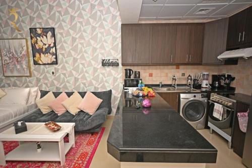a kitchen and a living room with a couch at Stylish Studio -Bright & Airy Al Reem Retreat in Abu Dhabi