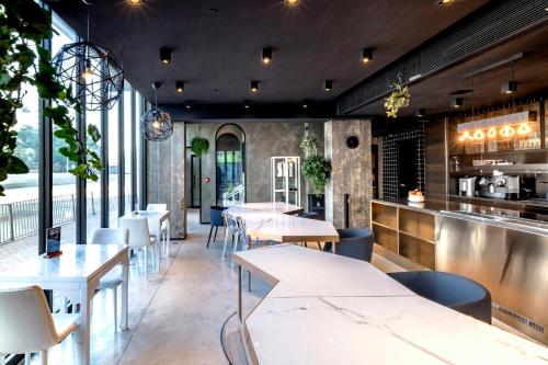 a restaurant with tables and chairs and windows at Oootopia Kai Tak in Hong Kong