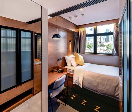 a small bedroom with a bed and a desk at Oootopia Kai Tak in Hong Kong