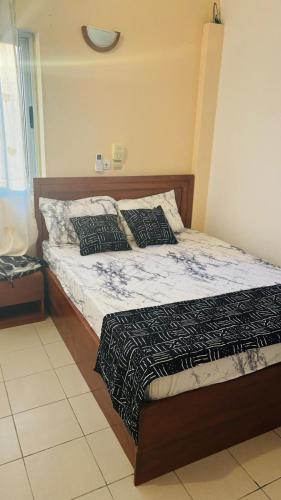 a bedroom with a bed with a wooden headboard at Appartement - BIOKOU - Route des pêches in Cotonou