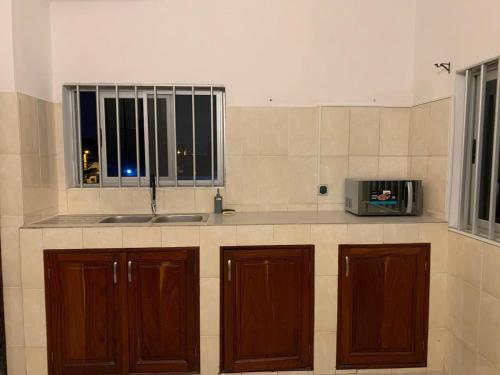 a kitchen with wooden cabinets and a sink and a microwave at Appartement - BIOKOU - Route des pêches in Cotonou