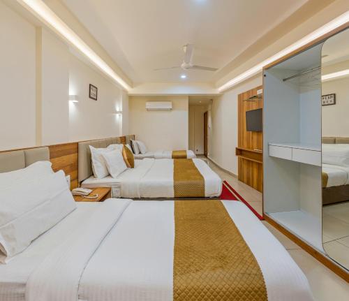 a hotel room with two beds and a tv at Hotel Kiyara in Kolhapur