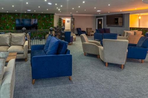 a lobby with couches and chairs and a television at Daresbury Park Hotel in Daresbury