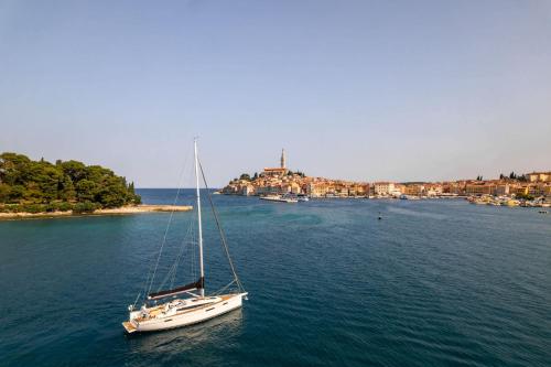 a sailboat in the water with a town in the background at Z6 Dolcevita Signature - Villa & Private Yacht in the Heart of Rovinj in Rovinj