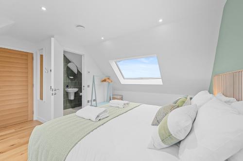 a white bedroom with a large bed with a window at An Teallach in Balmullo