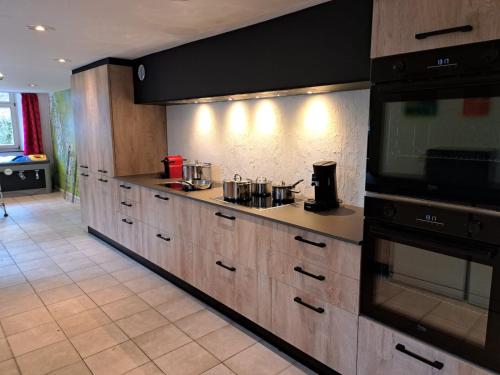 a large kitchen with wooden cabinets and a microwave at Moulin de Nawes in Herbeumont