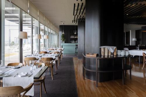 a restaurant with white tables and chairs and windows at Hotel Flor De Sal by The Editory in Viana do Castelo