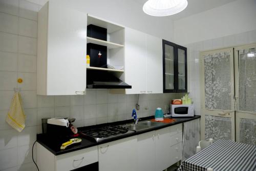 a white kitchen with a sink and a stove at Home's Vita in Trapani