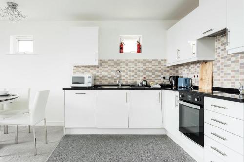 a kitchen with white cabinets and a sink at Beach Point - Stunning Harbour Views from Balcony in Poole