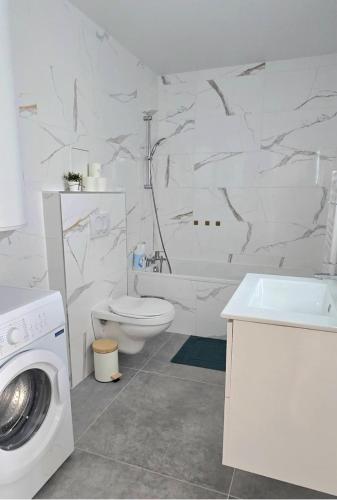 a white bathroom with a toilet and a washing machine at Le Freneusien, Wi-Fi parking in Freneuse