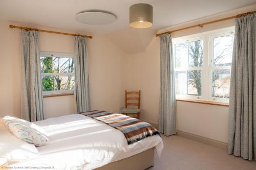 a bedroom with a bed and two windows at Craignair in Castle Douglas