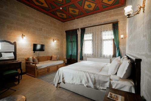 a bedroom with a bed and a couch and a television at Urgup Konak Hotel in Ürgüp