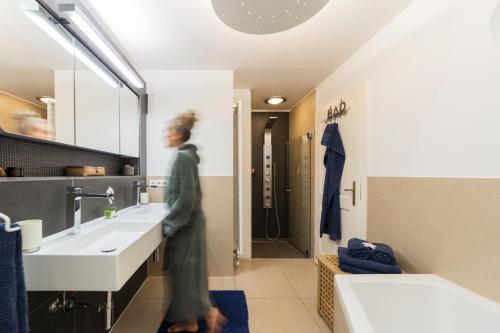 a woman is standing in a bathroom with two sinks at Traum FeWo mit Garten und Bergblick nahe Chiemsee in Übersee
