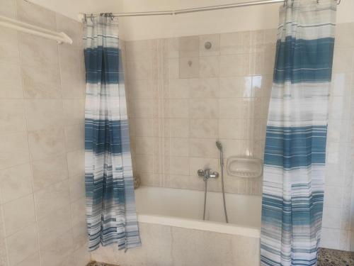 a shower with a blue and white shower curtain in a bathroom at Panorama Georgia's house in Áyios Vasílios