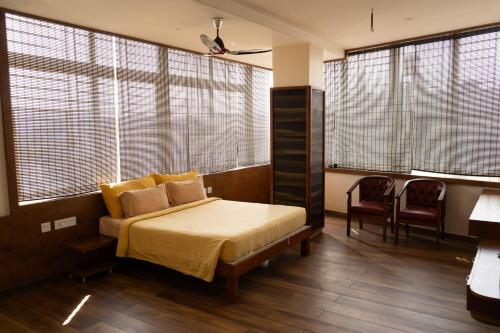 a bedroom with a bed and two chairs and windows at Hotel Grand Inn Jamkhandi in Jamkhandi