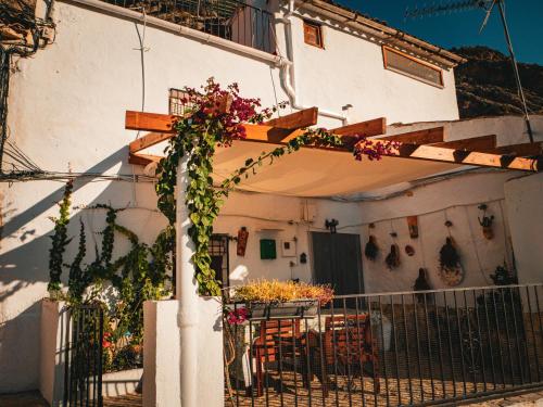 a white house with a table and flowers on it at Casa Rural Pilón Azul in Belerdas