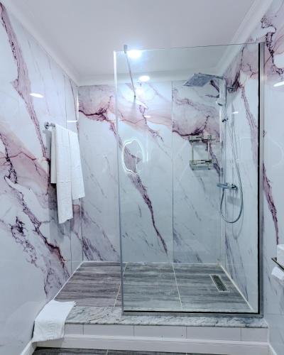a bathroom with a shower with pink marble at Atlantis Hotel Lagos in Lagos