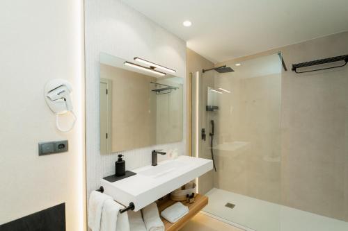 a white bathroom with a sink and a shower at L'Agora Rooms in Bocairent