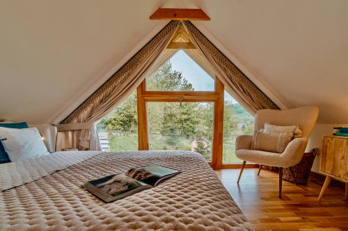a bedroom with a large window and a bed and a chair at Wygórowane - nowoczesne stodoły pod Tatrami in Brzegi
