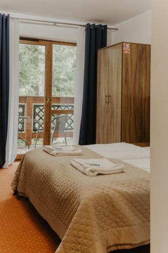 a bedroom with a bed with two towels on it at Holiday Family Pod Świerkami centrum miasta! in Szklarska Poręba