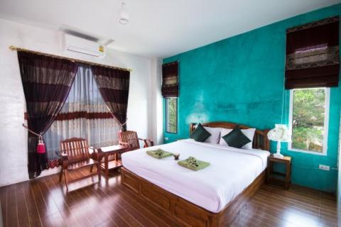 Un dormitorio con una gran cama blanca y una pared verde en รีสอร์ทที่ลำปาง (Resort At Lampang), en Lampang